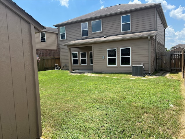 rear view of property featuring central air condition unit and a yard