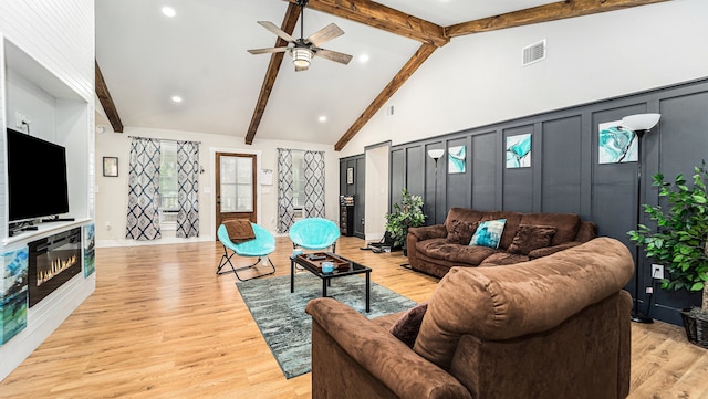 living room featuring high vaulted ceiling, light wood-type flooring, ceiling fan, and beam ceiling