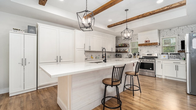 kitchen featuring beam ceiling, backsplash, a kitchen island with sink, stainless steel appliances, and hardwood / wood-style floors