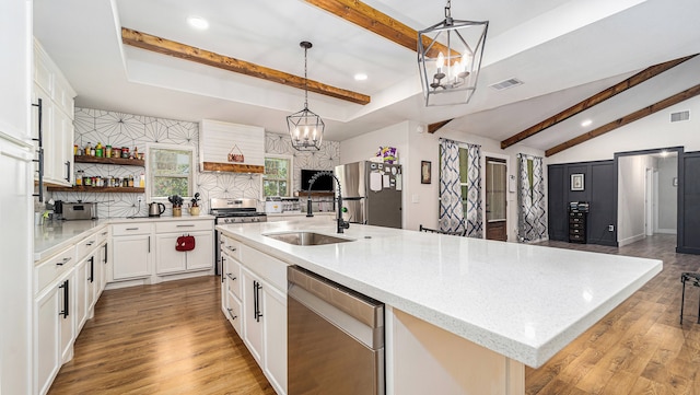 kitchen with tasteful backsplash, hanging light fixtures, a center island with sink, light hardwood / wood-style floors, and appliances with stainless steel finishes