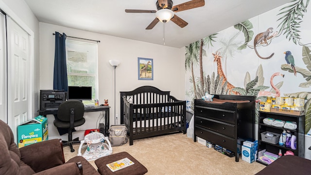 bedroom with light carpet, a closet, a crib, and ceiling fan