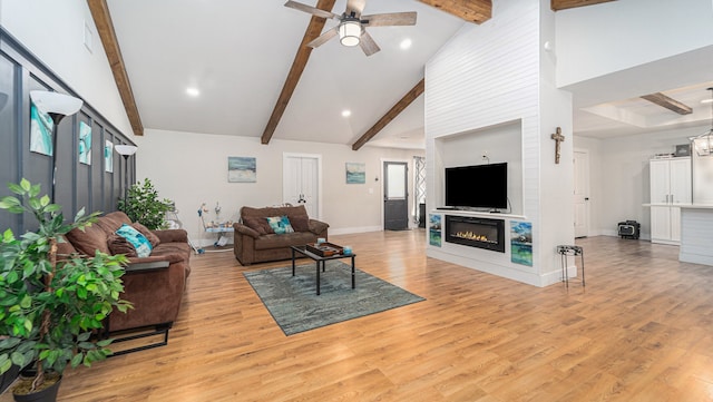 living room featuring beamed ceiling, light hardwood / wood-style flooring, a large fireplace, high vaulted ceiling, and ceiling fan