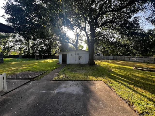 view of yard featuring a storage shed, a fenced backyard, a patio, and an outbuilding