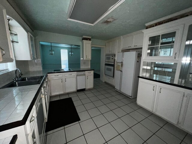 kitchen featuring white appliances, sink, tile countertops, light tile patterned flooring, and white cabinetry