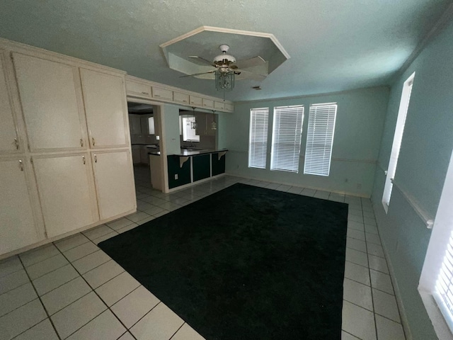 interior space with a textured ceiling, a wealth of natural light, light tile patterned flooring, and a ceiling fan