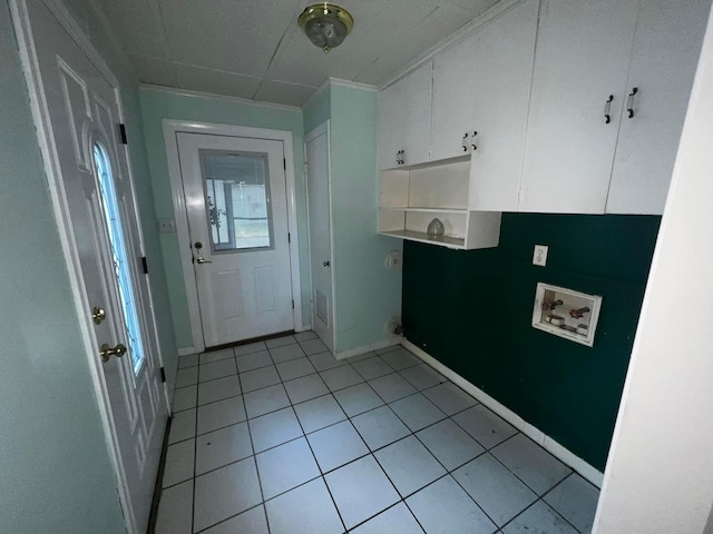 interior space featuring light tile patterned floors, hookup for a washing machine, cabinet space, and baseboards