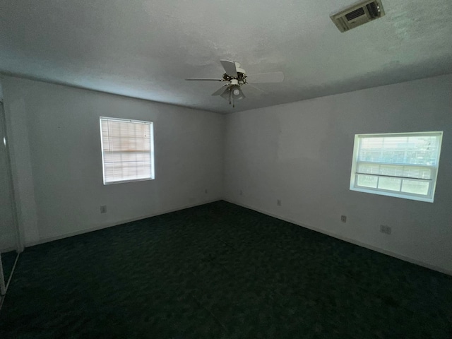 unfurnished room with a textured ceiling, ceiling fan, and carpet flooring