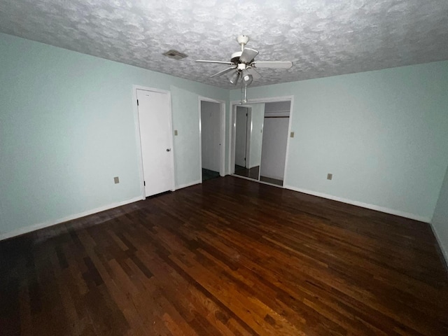 unfurnished bedroom featuring dark wood-style floors, a textured ceiling, visible vents, and baseboards