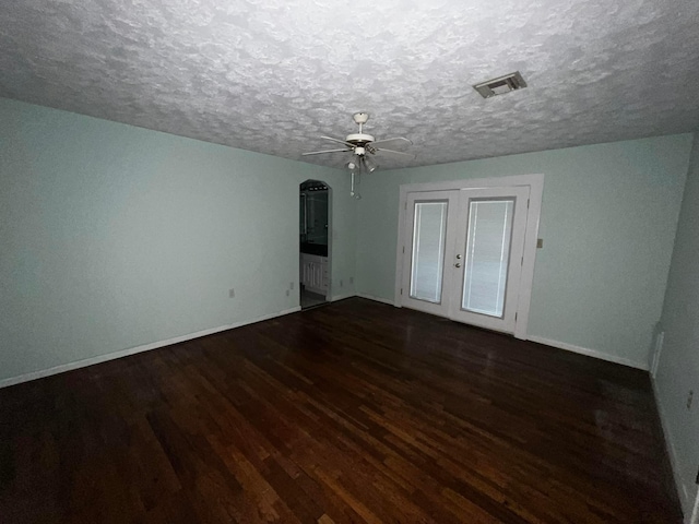 unfurnished room with ceiling fan, a textured ceiling, visible vents, baseboards, and dark wood finished floors