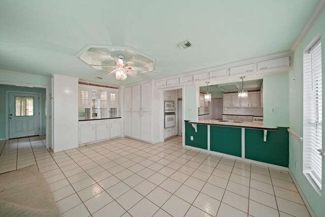 1826 E Ave, Katy, TX 77493 - kitchen with light tile patterned floors, a ceiling fan, ornamental molding, a peninsula, and white double oven