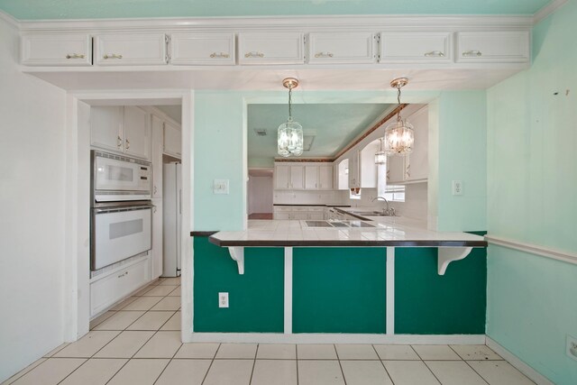1826 E Ave, Katy, TX 77493 - kitchen featuring white appliances, a chandelier, a sink, a peninsula, and a kitchen breakfast bar