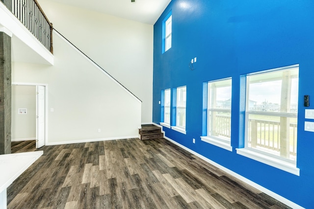 unfurnished living room with dark hardwood / wood-style flooring and a high ceiling