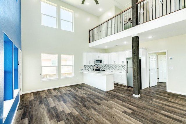 unfurnished living room with dark hardwood / wood-style floors, ceiling fan, and a high ceiling