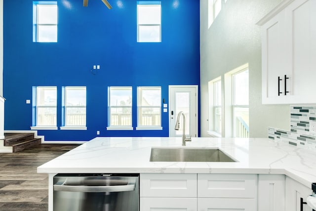 kitchen featuring light stone counters, dishwasher, sink, and white cabinets