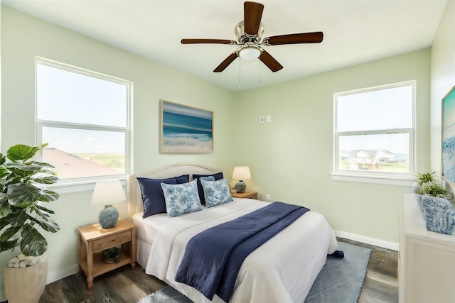 bedroom featuring ceiling fan, dark hardwood / wood-style floors, and multiple windows