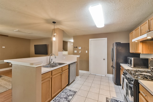 kitchen featuring a textured ceiling, pendant lighting, appliances with stainless steel finishes, sink, and light hardwood / wood-style flooring