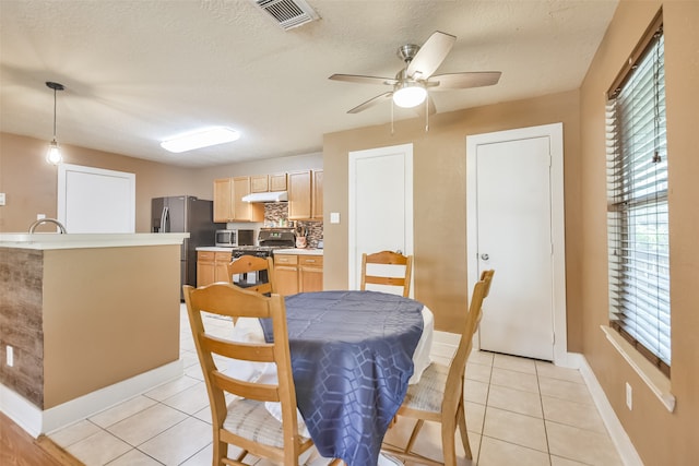 dining area featuring a textured ceiling, light tile patterned floors, sink, and ceiling fan