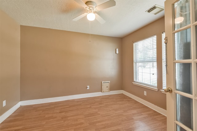 spare room featuring light hardwood / wood-style flooring, a textured ceiling, ceiling fan, and a healthy amount of sunlight