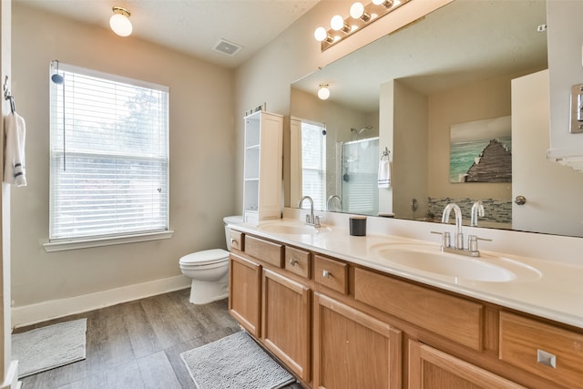 bathroom featuring wood-type flooring, toilet, plenty of natural light, and dual bowl vanity