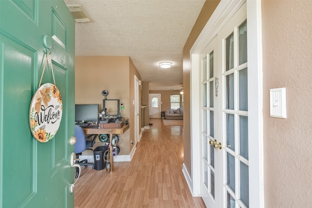 entryway featuring french doors, a textured ceiling, and light wood-type flooring