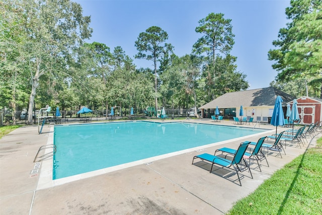 view of pool featuring a patio and an outbuilding