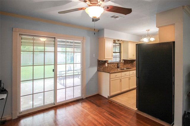 kitchen featuring backsplash, light wood-type flooring, black fridge, and sink