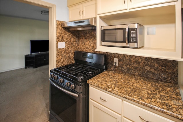 kitchen with dark stone counters, white cabinetry, wall chimney range hood, black gas range, and carpet