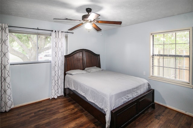 bedroom featuring ceiling fan, multiple windows, and dark hardwood / wood-style flooring