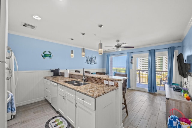 kitchen featuring decorative light fixtures, white cabinetry, sink, a breakfast bar area, and white dishwasher