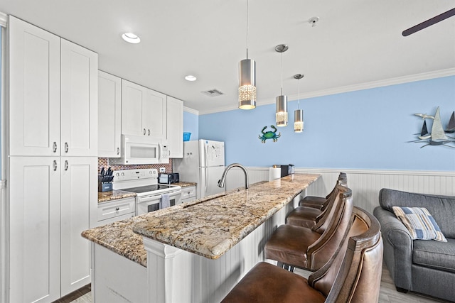 kitchen featuring white cabinetry, pendant lighting, light stone counters, and white appliances