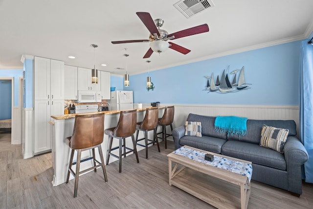 living room with ornamental molding, ceiling fan, and light hardwood / wood-style flooring