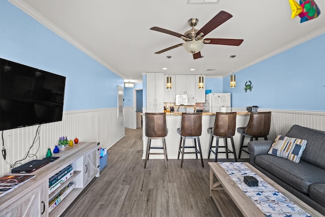 living room with crown molding, dark hardwood / wood-style floors, and ceiling fan