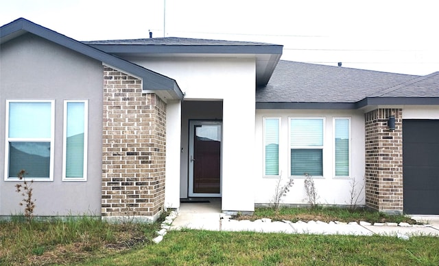 doorway to property featuring brick siding, roof with shingles, and stucco siding