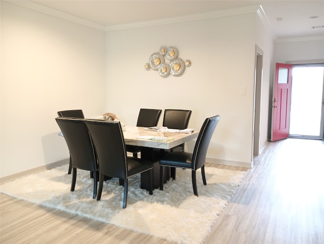 dining area with ornamental molding and light hardwood / wood-style floors