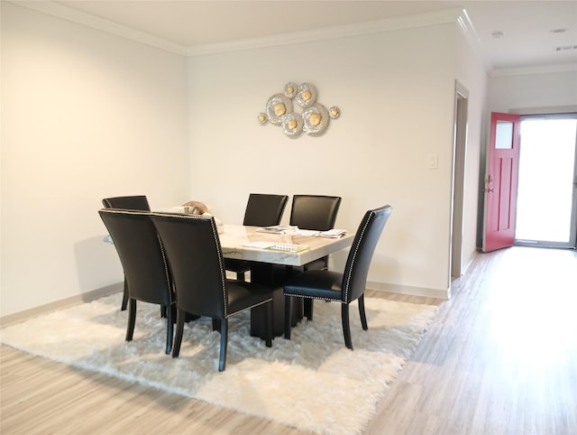 dining space featuring light wood-style flooring, baseboards, and ornamental molding