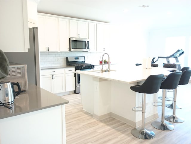 3335 Balboa Grove Ln, Missouri City, TX 77459 - kitchen with light wood-type flooring, white cabinetry, backsplash, stainless steel appliances, and a sink