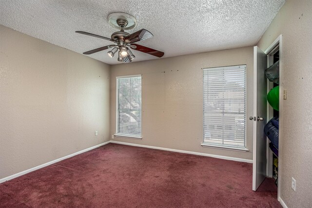 carpeted spare room featuring a textured ceiling and ceiling fan