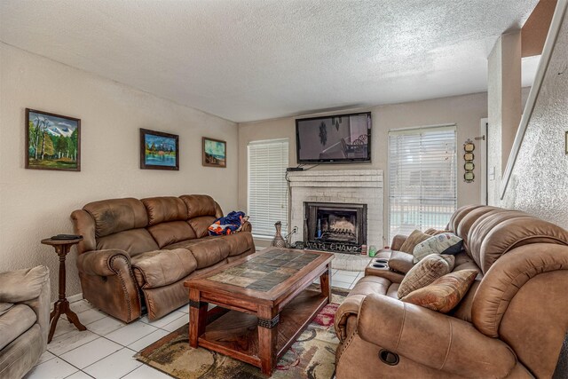 living room with a fireplace, light tile patterned floors, and a textured ceiling