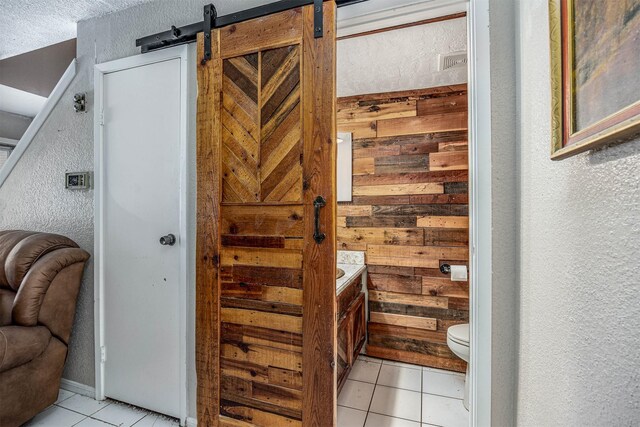 interior space featuring vanity, tile patterned floors, a textured ceiling, and toilet