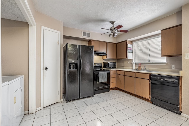 kitchen featuring light tile patterned floors, ceiling fan, washing machine and clothes dryer, black appliances, and sink