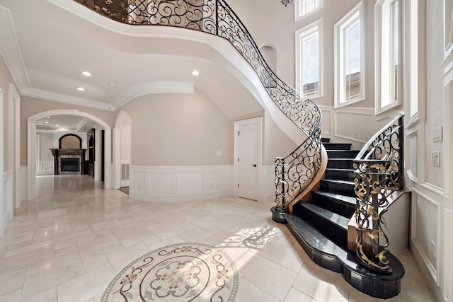 entrance foyer with a towering ceiling, light tile patterned floors, and ornamental molding