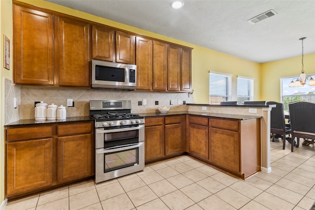 kitchen with kitchen peninsula, stainless steel appliances, backsplash, decorative light fixtures, and a notable chandelier