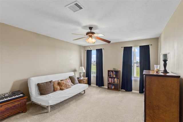 sitting room featuring ceiling fan, light colored carpet, and a textured ceiling