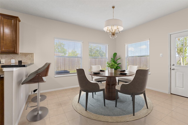 tiled dining space featuring a healthy amount of sunlight and a chandelier