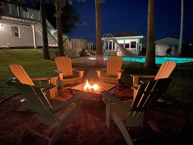 patio at night featuring a fire pit and an outdoor pool