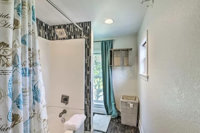 full bathroom with shower / bath combo, baseboards, wood finished floors, and a textured wall