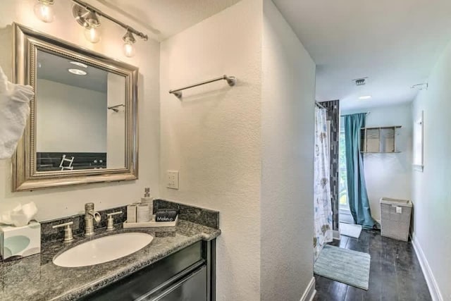 bathroom featuring wood finished floors, vanity, visible vents, and baseboards