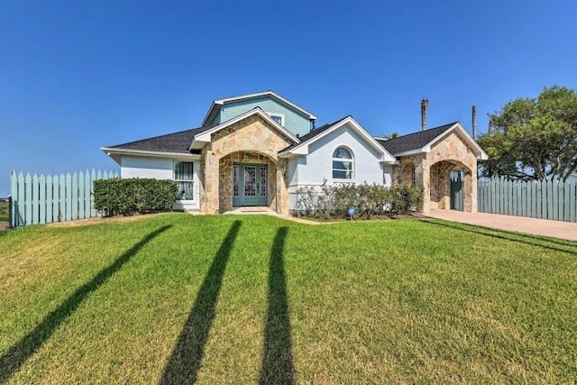 view of front of home with stone siding, fence, and a front lawn