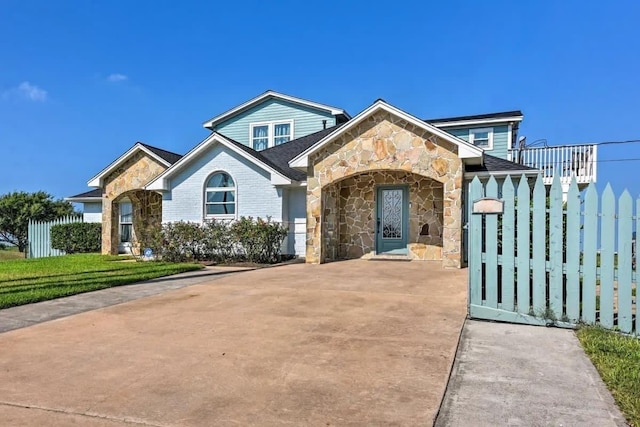 view of front of home featuring stone siding, a front yard, and driveway