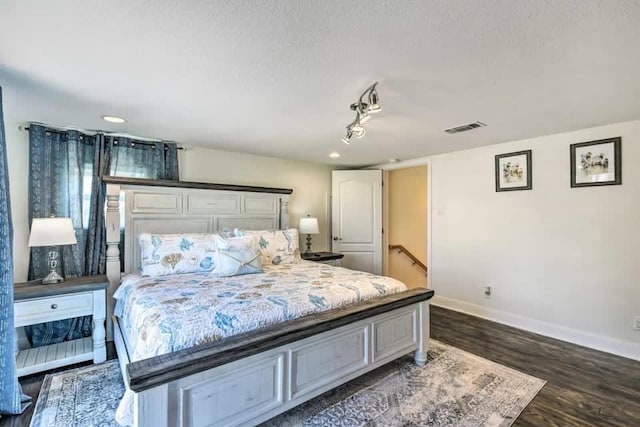 bedroom featuring dark wood-style flooring, visible vents, a textured ceiling, and baseboards